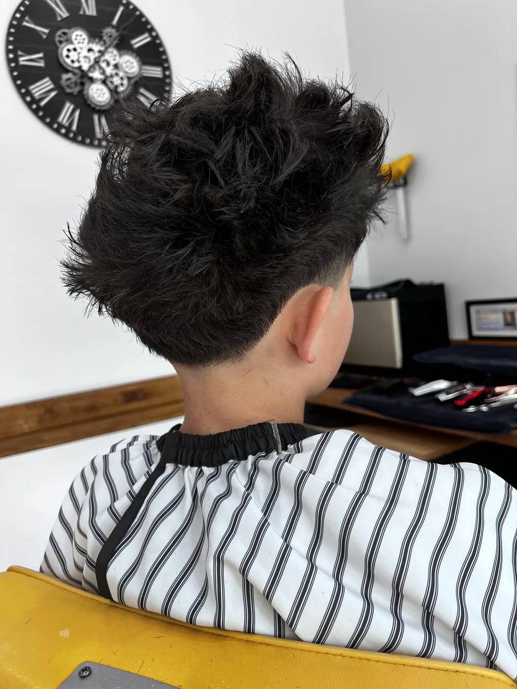 Low taper fade with textured fringe haircut at The Gilded Edge barbershop, West Seattle